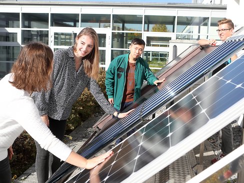 Studierende stehen vor verschiedenen Solarmodulen und berühren diese.