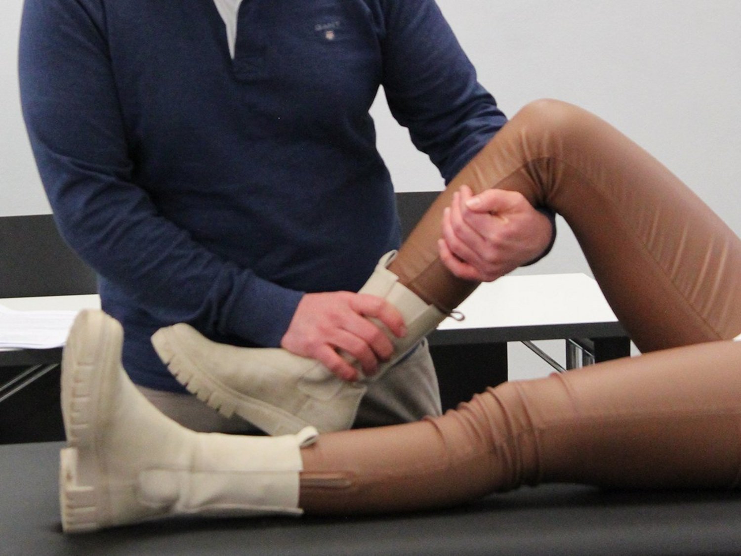 Ein Dozent untersucht das Knie einer Patientin.