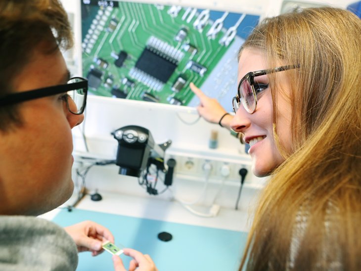 Zwei Studierende betrachten die Vergrößerung einer elektronischen Schaltung.
