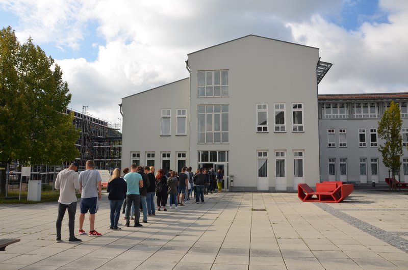 Eine Schlange neuer Studenten reiht sich vor dem Verwaltungsgebäude auf. Sie warten, um sich für das Studium zu immatrikulieren.