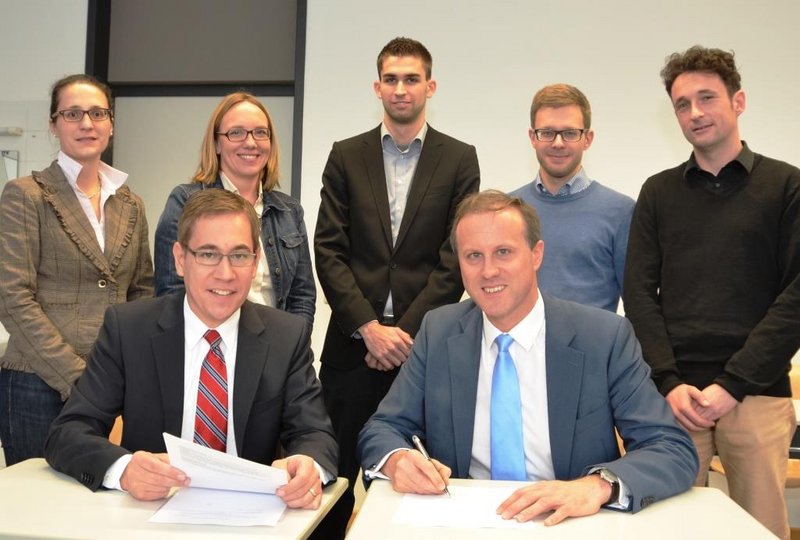 Professor Dr. Bernd Mühlfriedel (vordere Reihe rechts) unterzeichnet im Beisein des Notars Christian Steer (vordere Reihe links) die Gründungsurkunde der Campus Company Landshut UG. Hintere Reihe von links: Katrin Barth und Prof. Dr. Sandra Gronover von