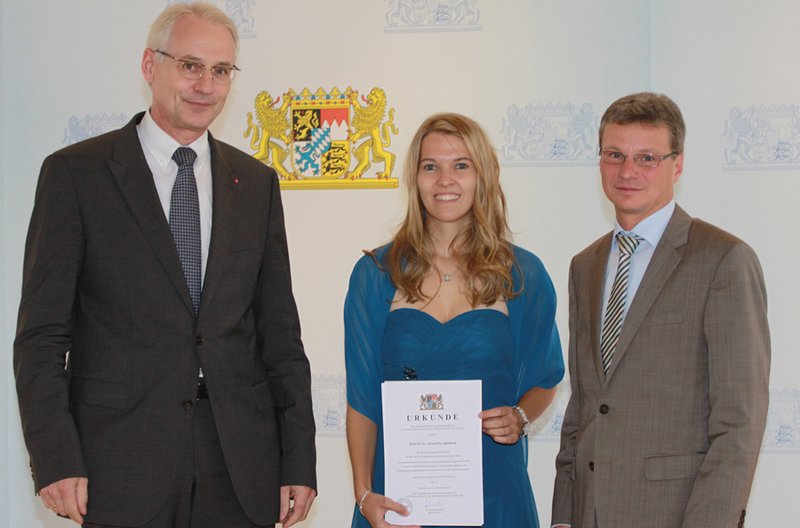 Die Preisträgerin Alexandra Apfelbeck mit Staatssekretär Bernd Sibler (re.) und Hochschulpräsident Prof. Dr. Karl Stoffel (li.)