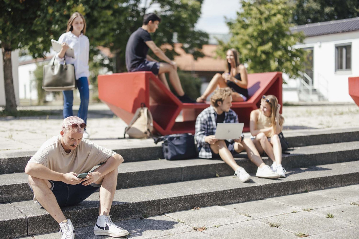 Studierende sitzen draußen an einem Enzo und unterhalten sich