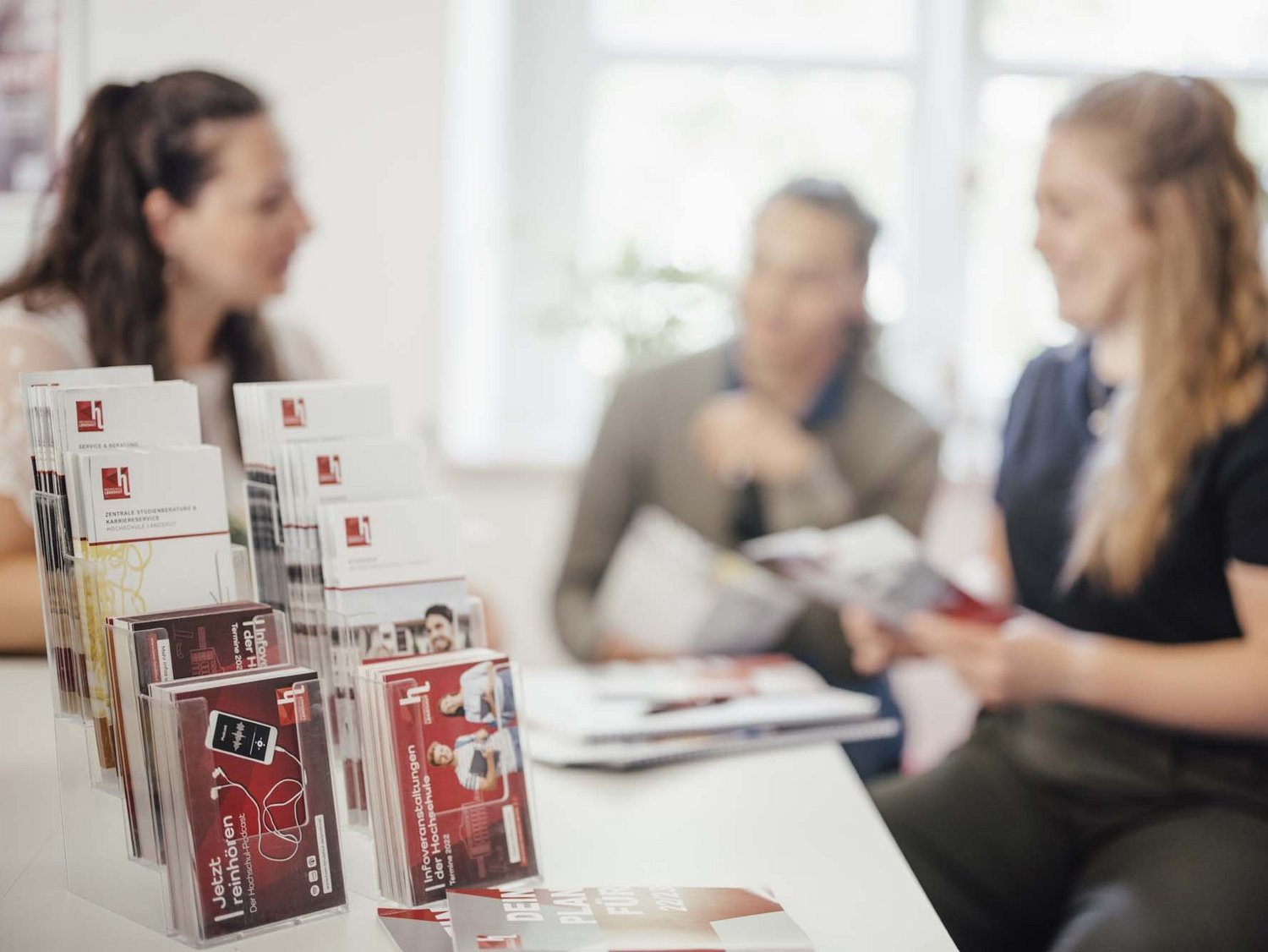 Infomaterial der Hochschule mit Personen im Hintergrund