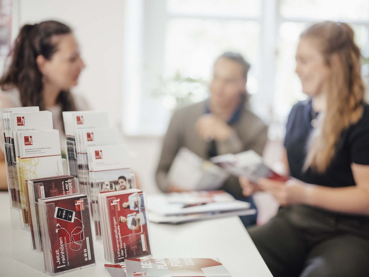 Infomaterial der Hochschule mit Personen im Hintergrund