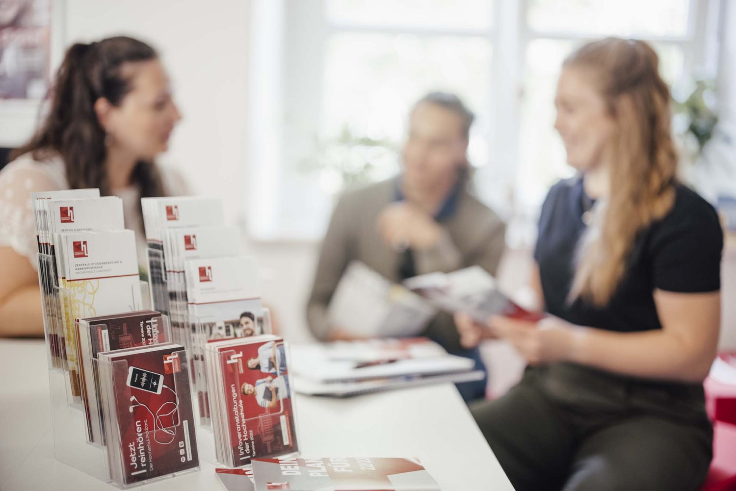 Infomaterial der Hochschule mit Personen im Hintergrund