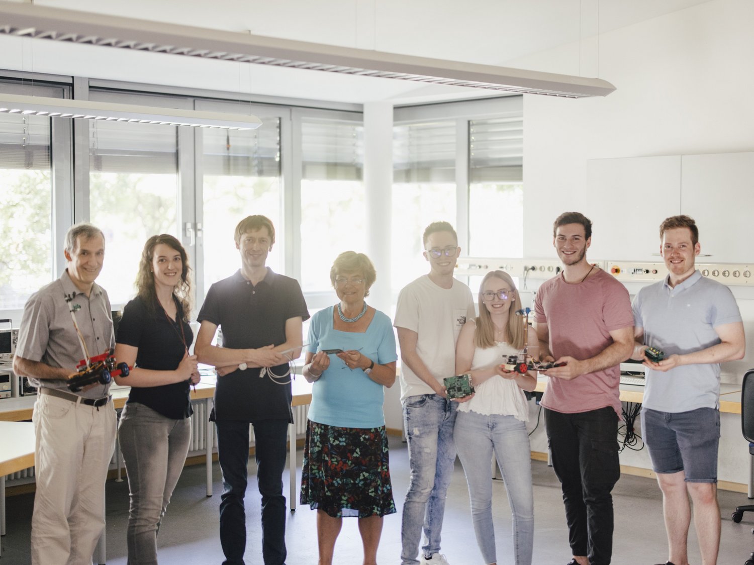 Studierende und Professoren der Fakultät stehen im Labor mit Projektbeispielen.