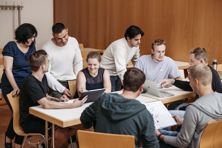 Man sieht eine Gruppe an Personen zusammen eine Projektarbeit machen.