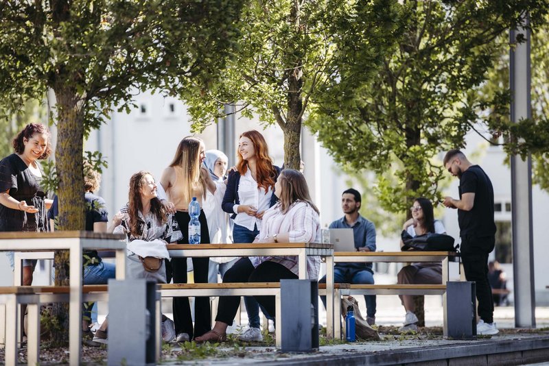 Mehrere Personen sitzen draußen zusammen an einem Tisch.