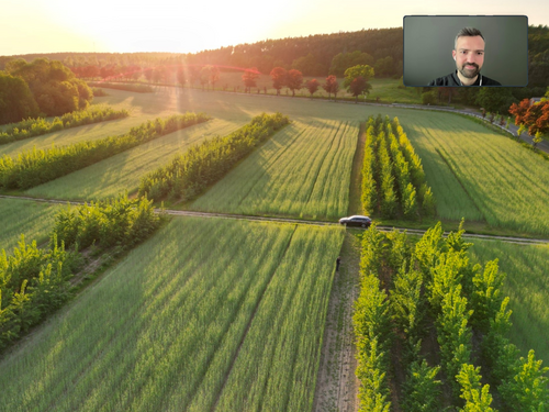 Man sieht ein Auto durch eine grüne Landschaft fahren.