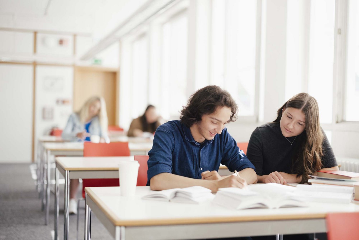 Zwei Personen sitzen an einem Tisch nebeneinander.