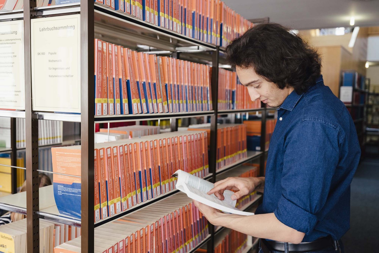 Eine Person steht vor einer Reihe an Büchern.