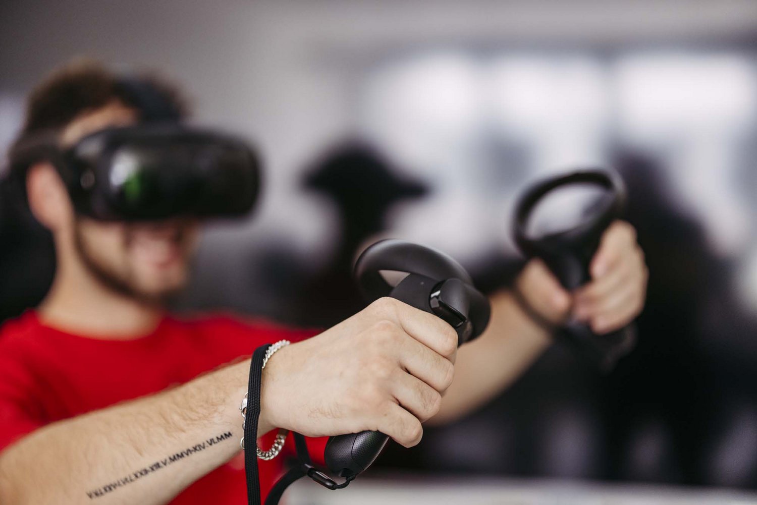 Eine Person trägt eine Virtual Reality-Brille und hat jeweils einen Kontroller in einer Hand.