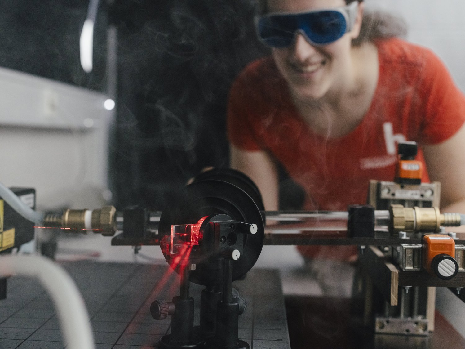 Eine Person mit Schutzbrille betrachtet Laserstrahlen.