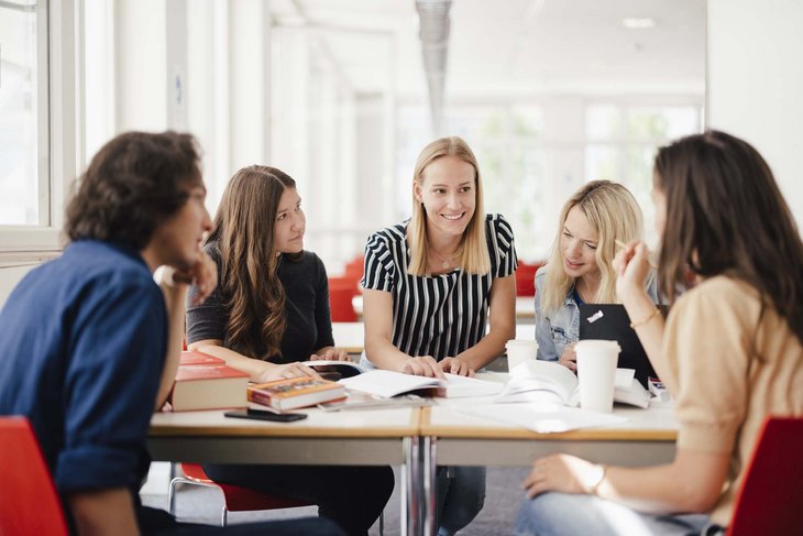 Eine Gruppe sitzt am Tisch und arbeitet zusammen