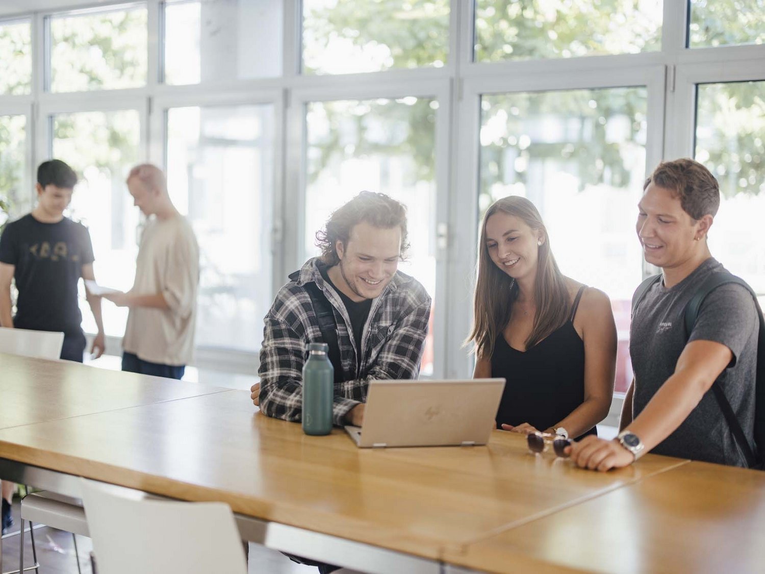 Studierende unterhalten sich an den Hochtischen bei der Cafeteria