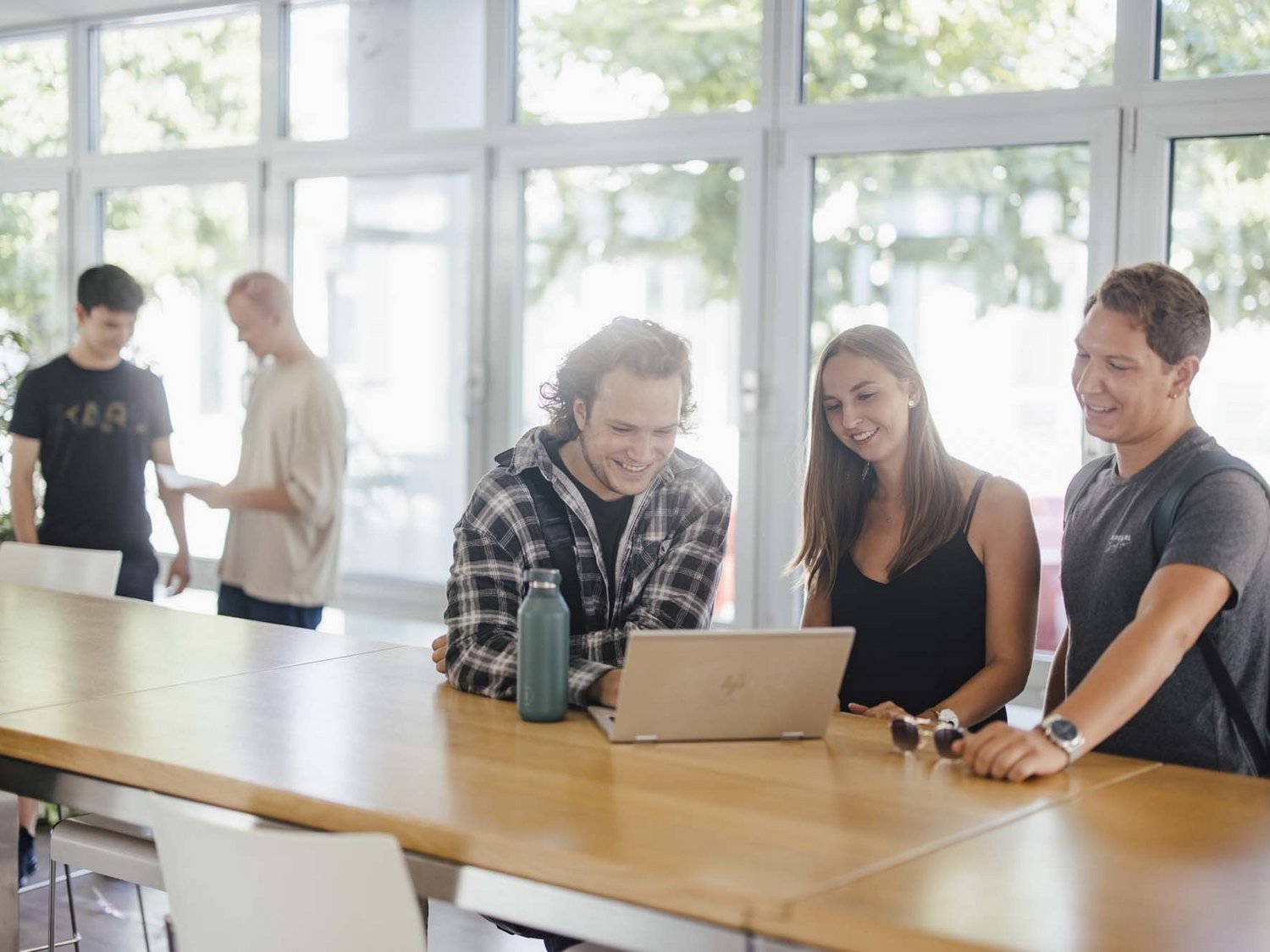 Studierende unterhalten sich an den Hochtischen bei der Cafeteria