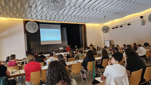 Zuhörende sitzen in einem großen Hörsaal bei einem Vortrag.
