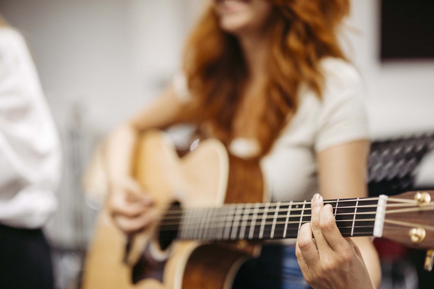 Man sieht eine Gitarre und zwei Finger vorne auf der Gitarre liegen.