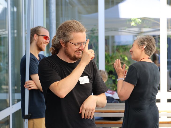 Ein gehörloser Mitarbeiter gebärdet auf einer Veranstaltung der Hochschule Landshut.