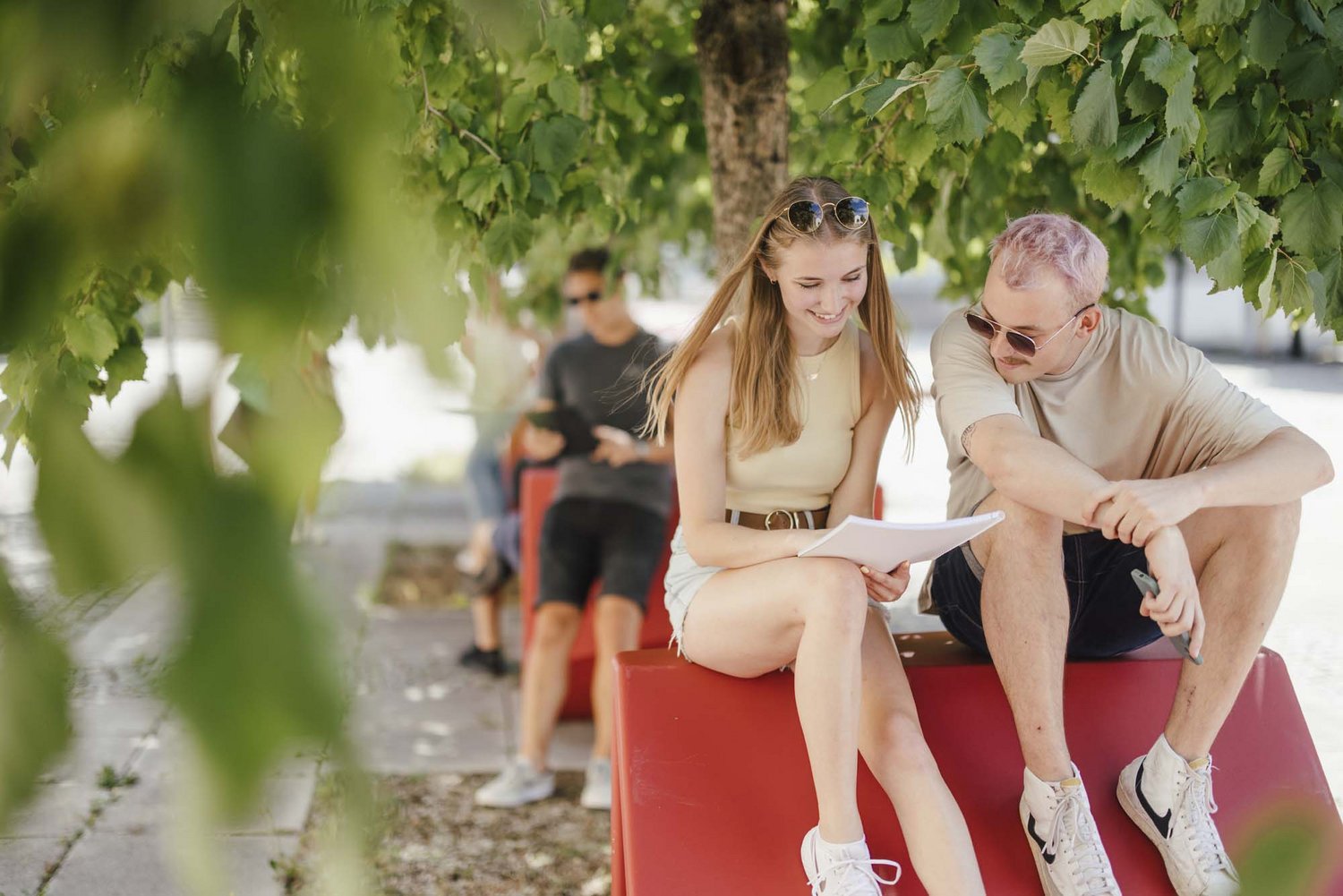 Studierende sitzen draußen an einem Enzo und unterhalten sich