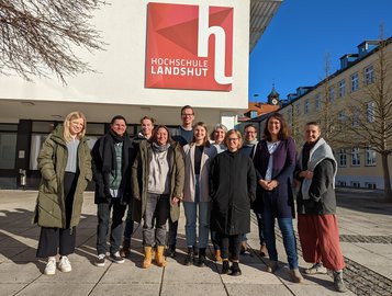 Eine Gruppe Menschen steht vor dem D-Gebäude