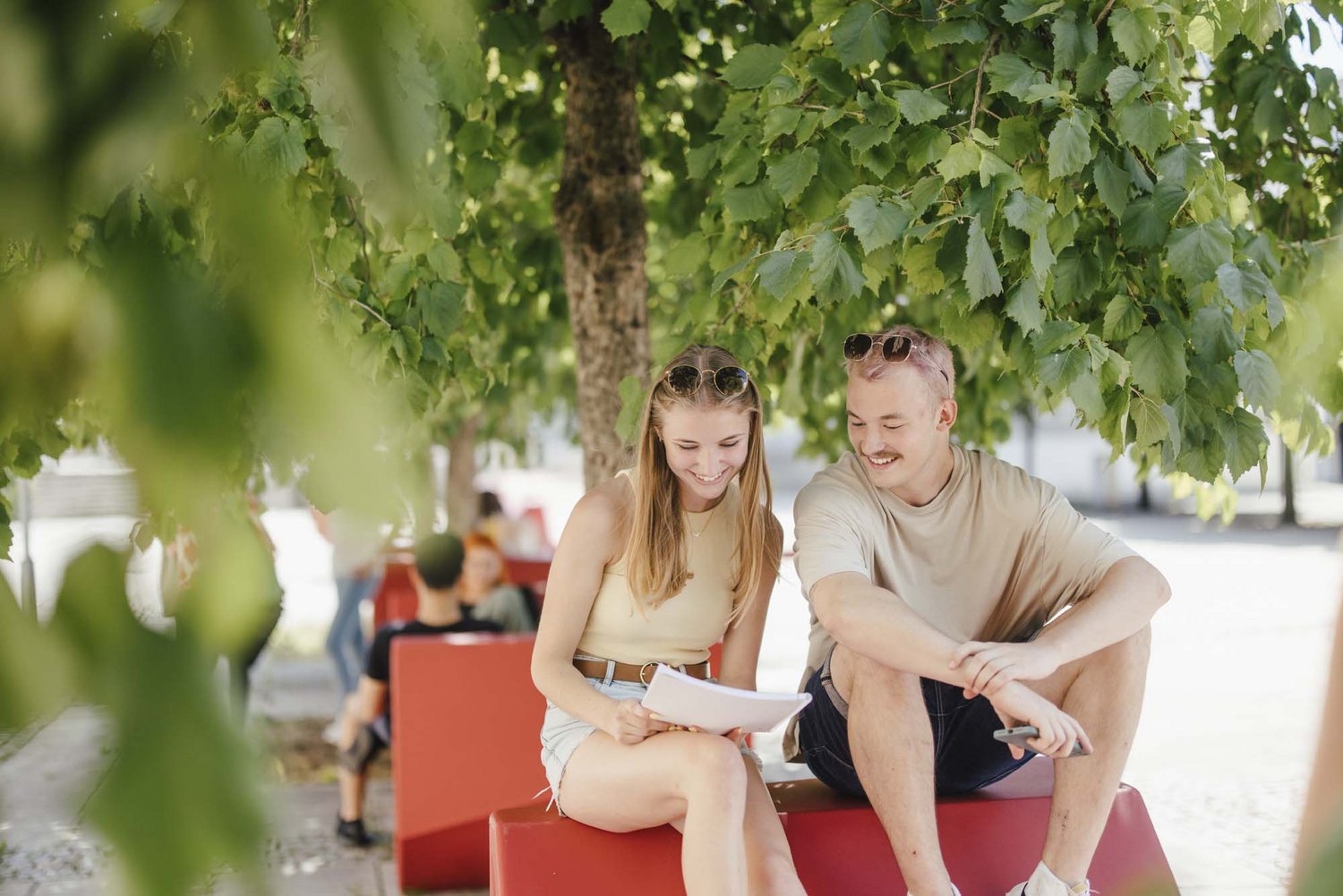 Studierende sitzen draußen an einem Enzo und unterhalten sich