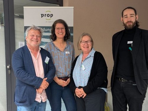 Gruppe Personen steht vor einem Aufsteller von Prop e.V.