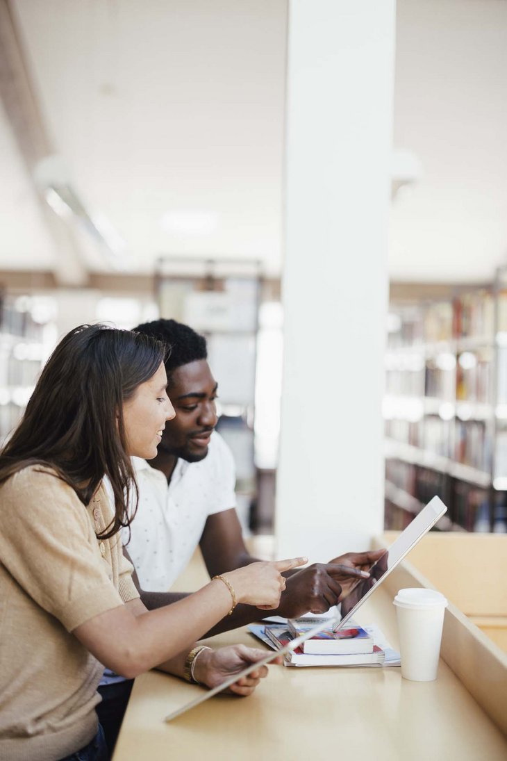 Zwei Personen erklären sich etwas gegenseitig an einem Stehplatz von der Bibliothek