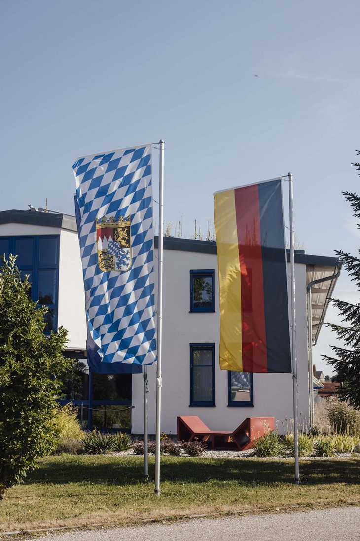 Man sieht zwei Flaggen einmal die bayrische Flagge einmal die deutsche Flagge.