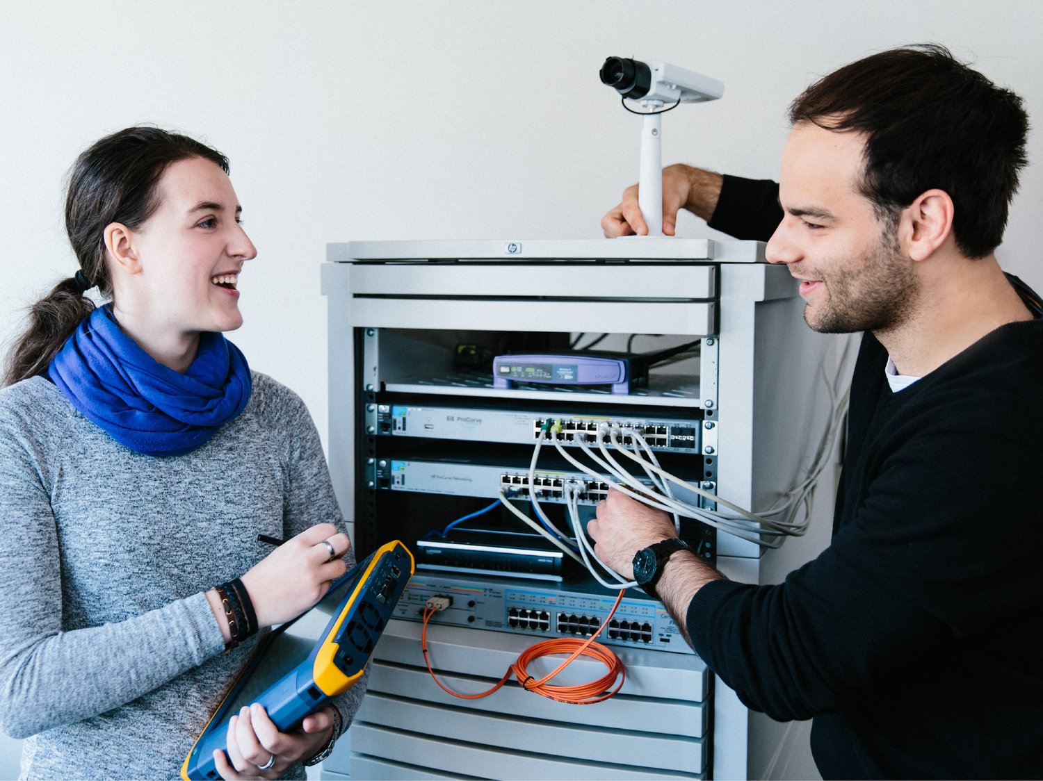 Zwei Studierende untersuchen einen Aufbau mit Netzwerkkomponenten.