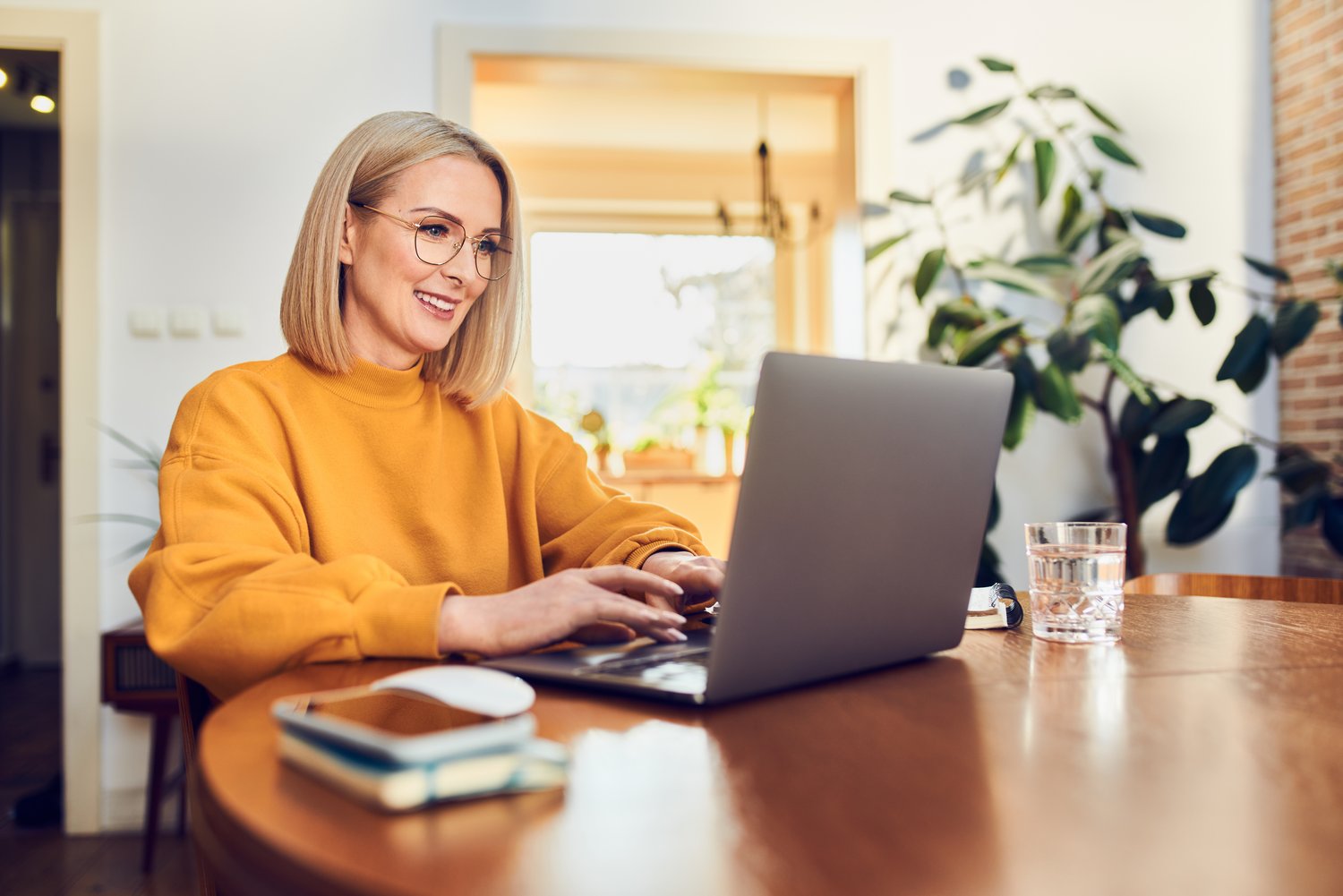 Portrait of middle aged woman sitting at dinning with laptop wor