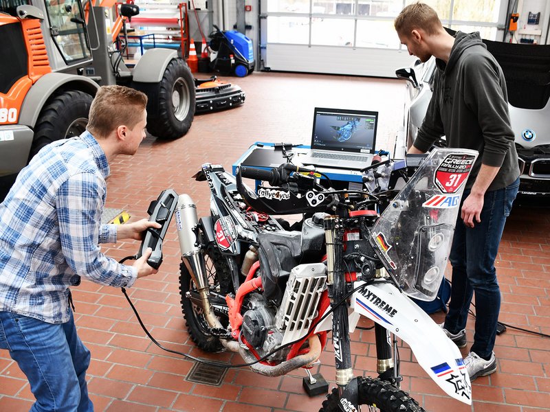 Lutz Prager (l.) und Jonas Englberger (r.) beim Scannen des Rallye-Motorrades