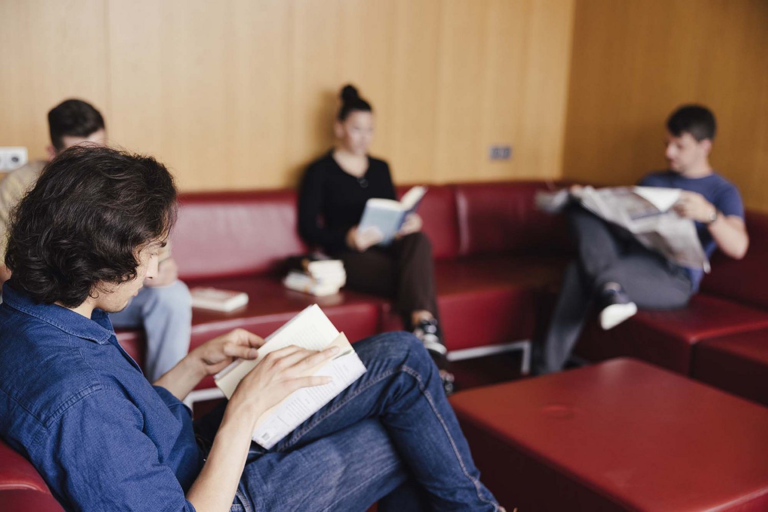 Eine Person sitzt auf einer Couch und liest ein Buch.