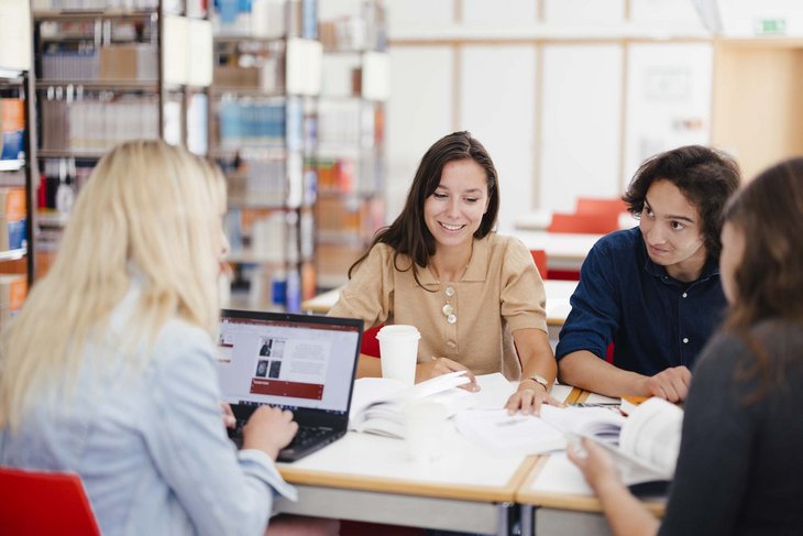 Eine Gruppe sitzt am Tisch und arbeitet zusammen