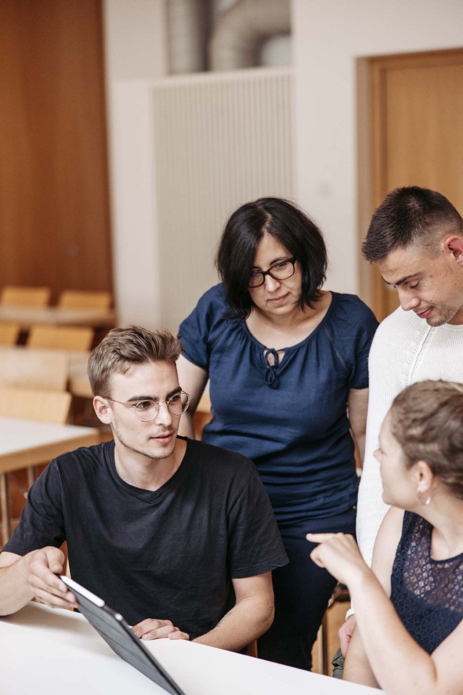 Man sieht vier Personen zusammen eine Projektarbeit machen.