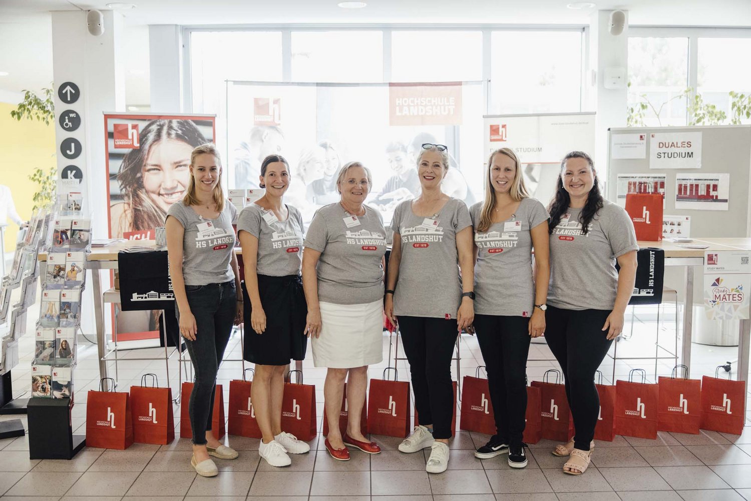 Sechs Personen stehen vor einem Stand in der Hochschule.