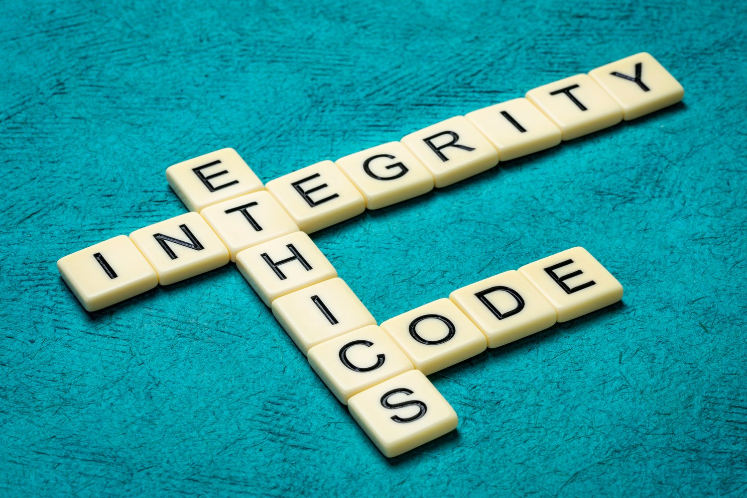 Steine aus dem Spiel Scrabble formen die Worte Integerity, Ethics und Code
