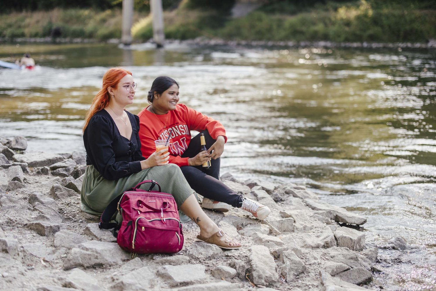 Zwei Personen sitzen am Wasser mit Ihren Getränken