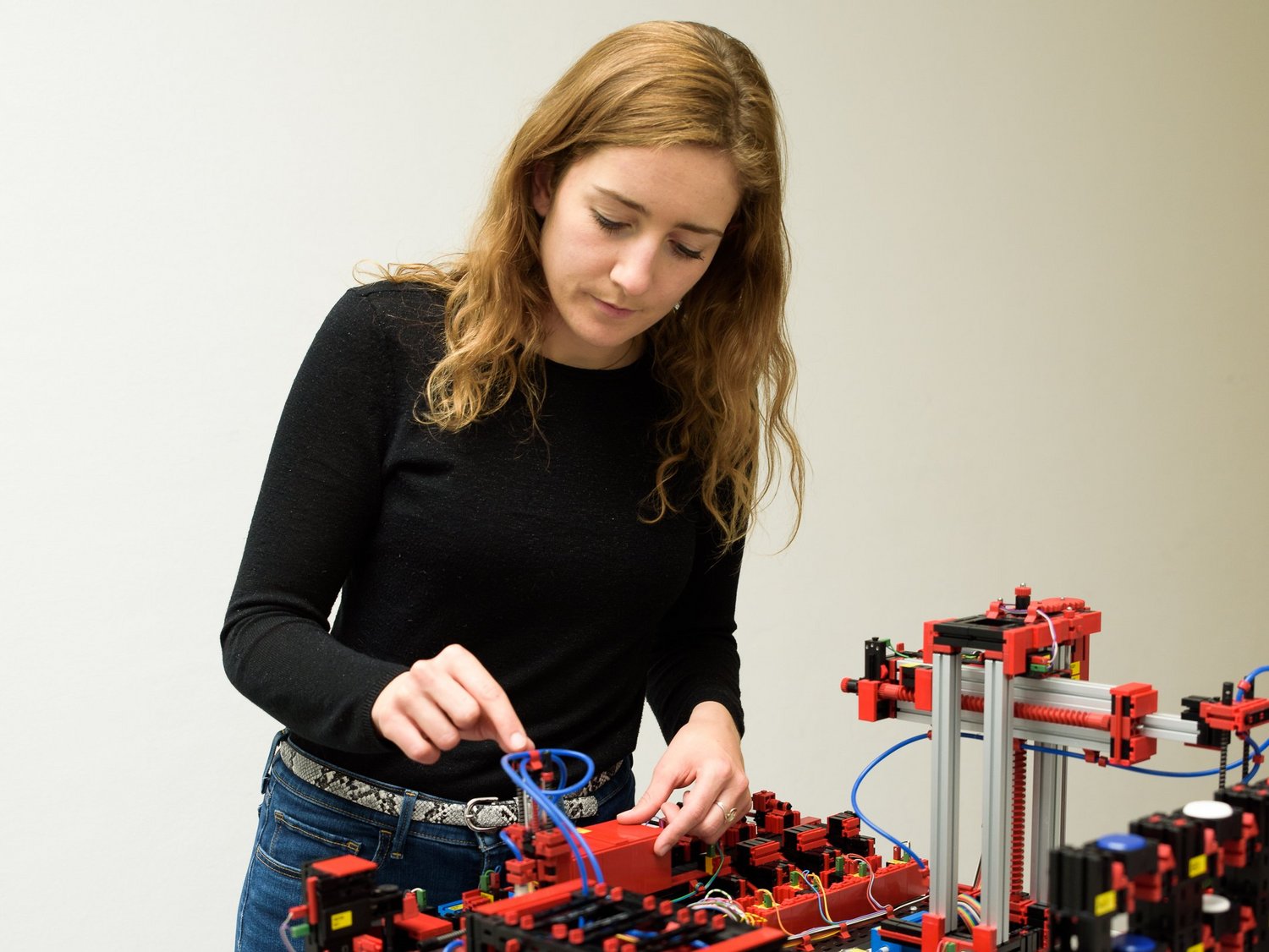 Eine junge Frau steht interessiert vor einem Demonstrationsaufbau für Industrie 4.0. 