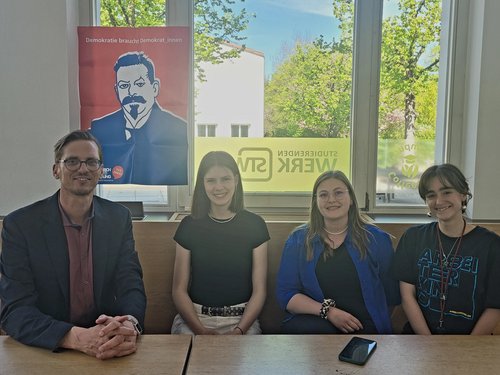 4 Personen sitzen an einem Tisch