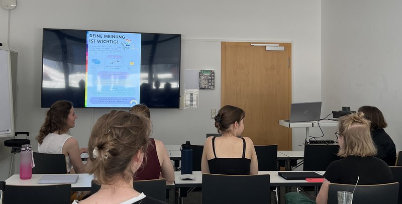 Gruppe Studierender sitzt im Hörsaal und verfolgt eine Präsentation.