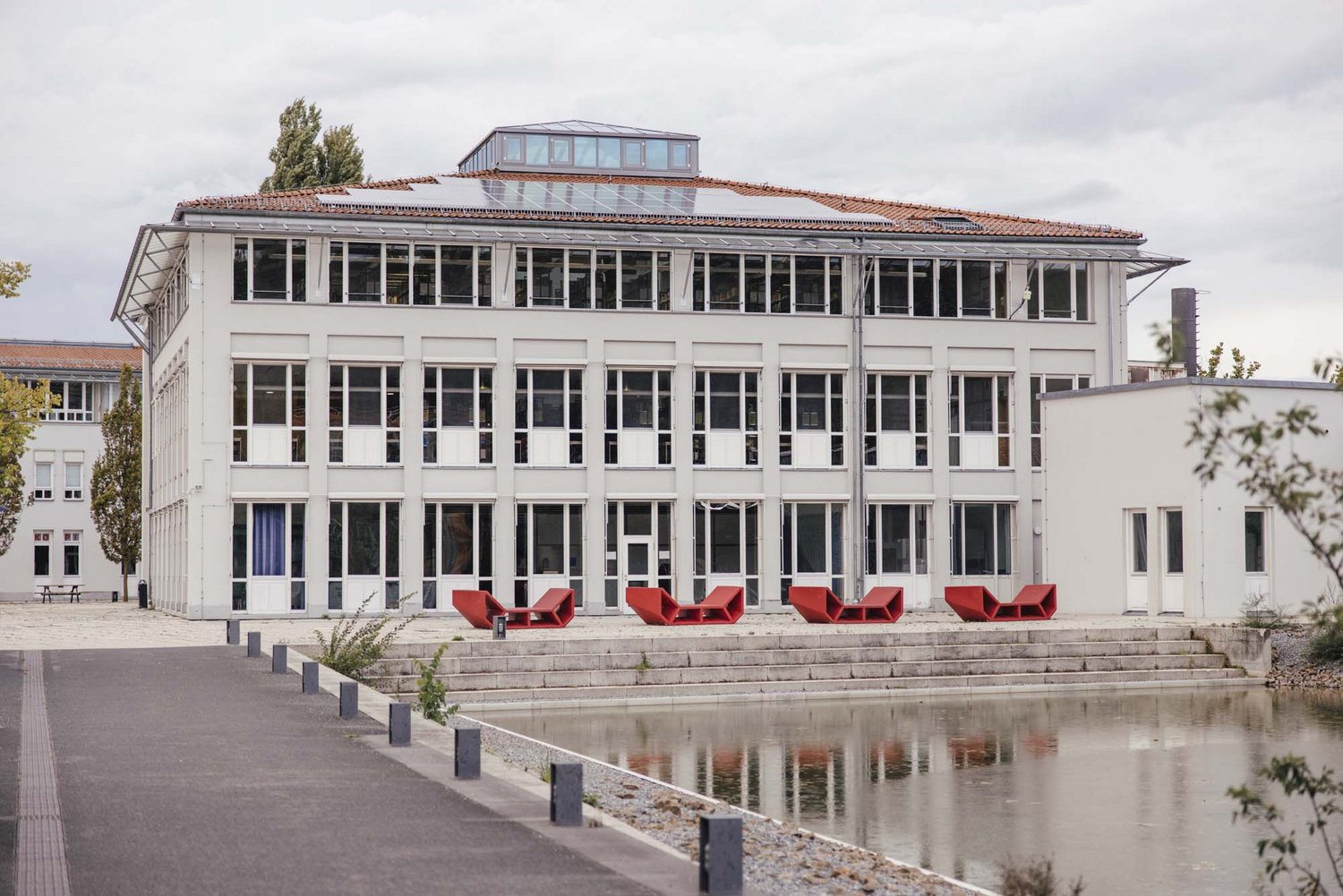 Man sieht einen Teich, im Hintergrund sieht man das B Gebäude.