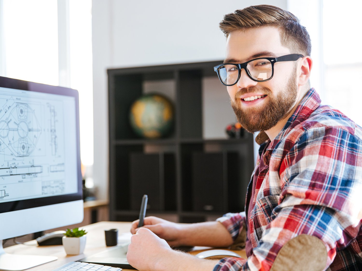 Eine Person sitzt vor einem PC-Bildschirm mit einer geöffneten Konstruktion.