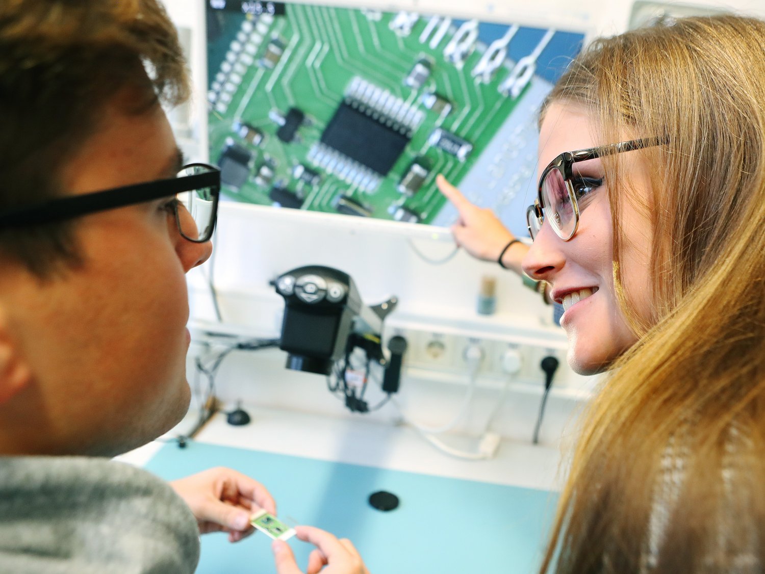 Zwei Studierende betrachten die Vergrößerung einer elektronischen Schaltung.