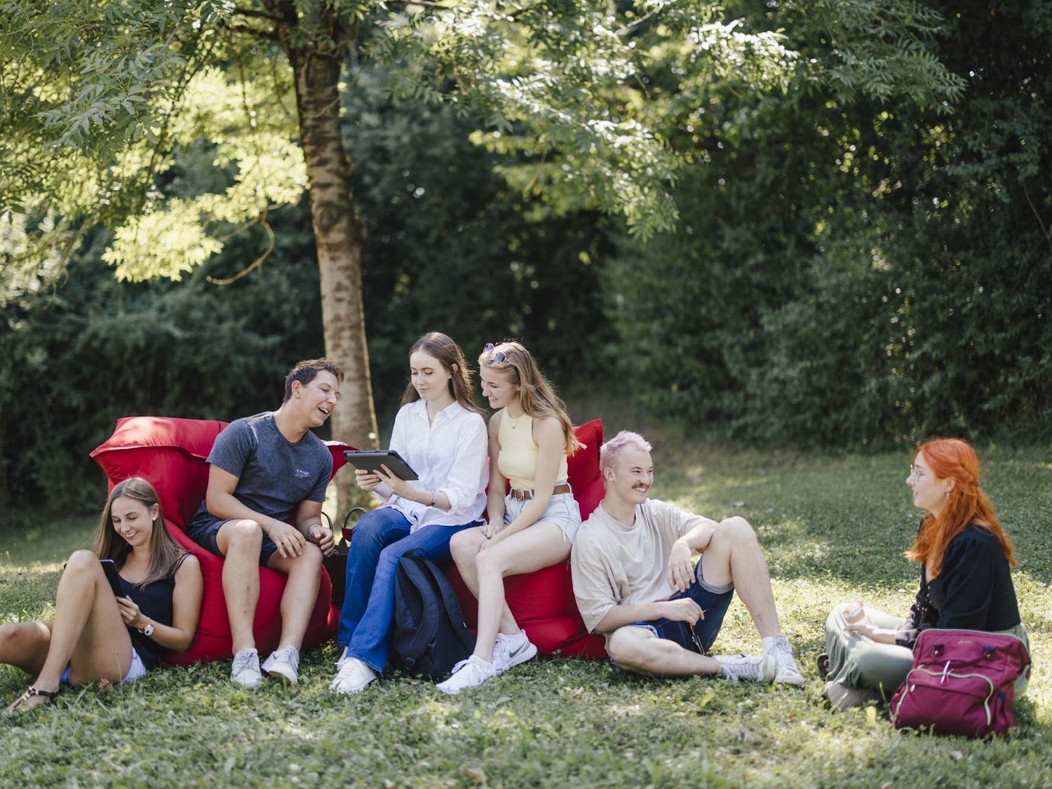 Studierende sitzen draußen auf Sitzsäcken und unterhalten sich