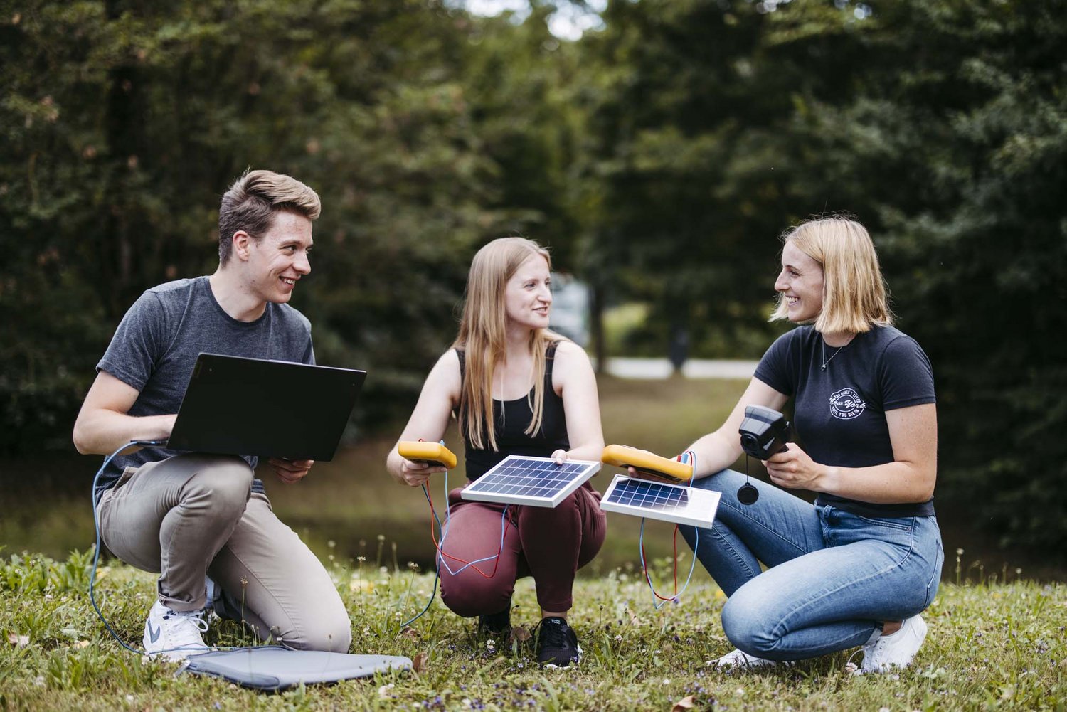 Drei Personen sind zu sehen zwei davon halten sowohl ein Solarstrommesser als auch eine Solarscheibe in der Hand die letzte Person hält einen Computer in der Hand.