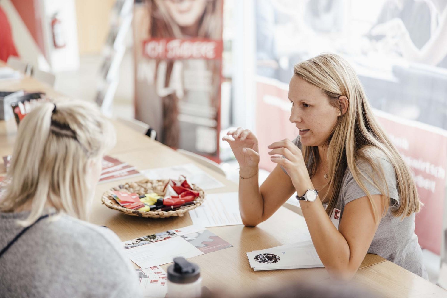 Eine Person sitzt an einem Stand in der Hochschule.