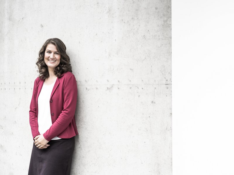 Prof. Dr. Katrin Liel lehnt an einer Wand und schaut in die Kamera