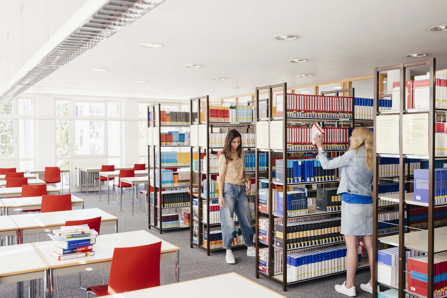 Zwei Personen stehen gegenüber zwischen ihnen eine Bücherwand.